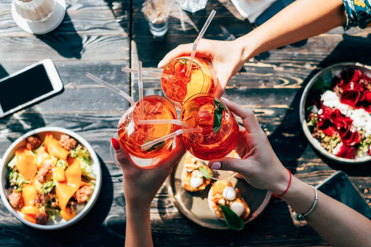 Overhead view of three women making a celebratory toast with Spritz cocktails