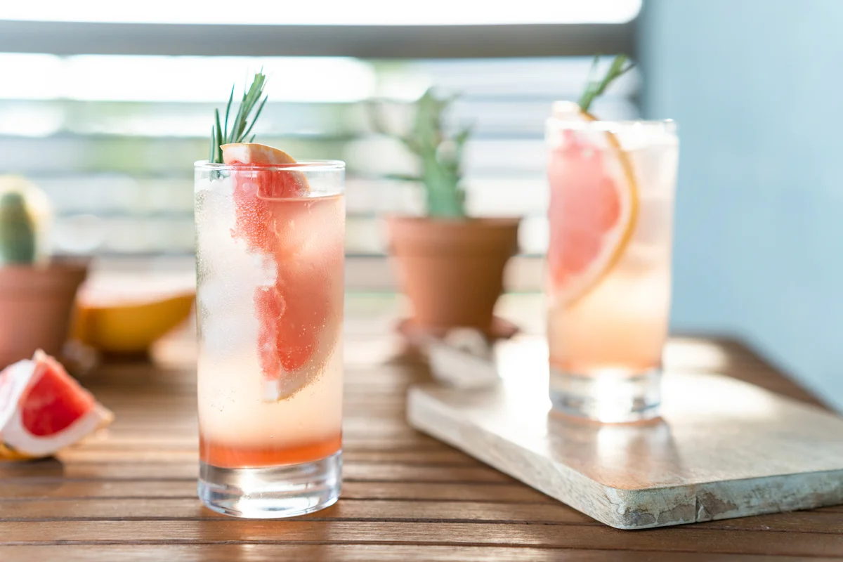 Two glasses of vodka with fresh grapefruit and grapefruit segments on a table