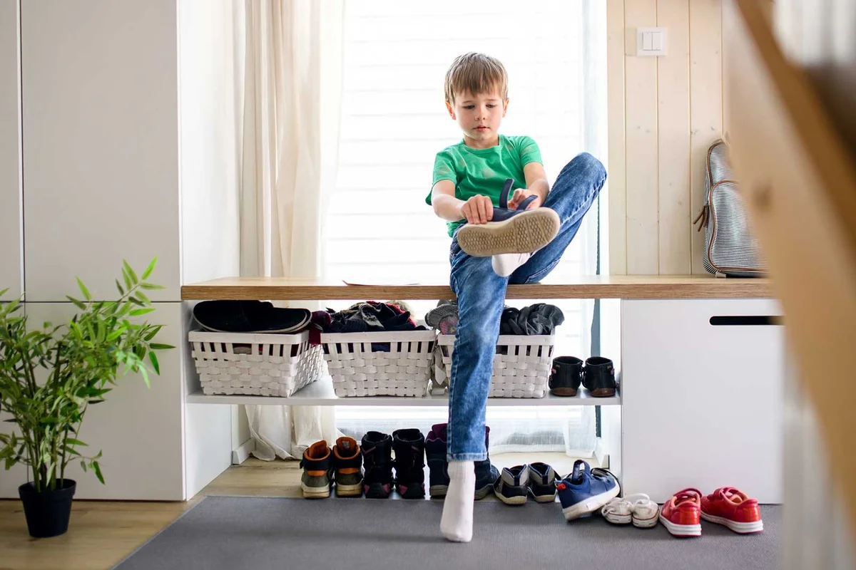 boy putting on shoes at front door