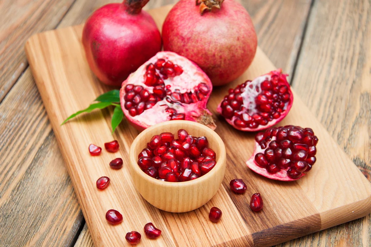 Pomegranates with grains on a wooden background