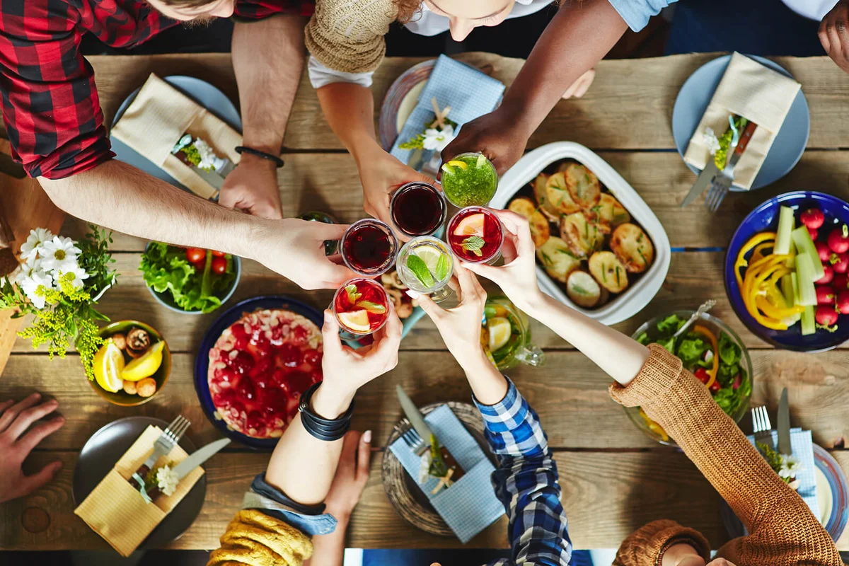 Friends toasting with cocktails at dinner table