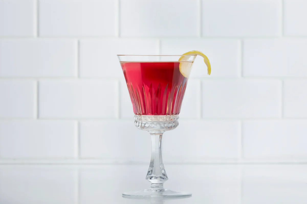 Red cocktail with a lemon garnish