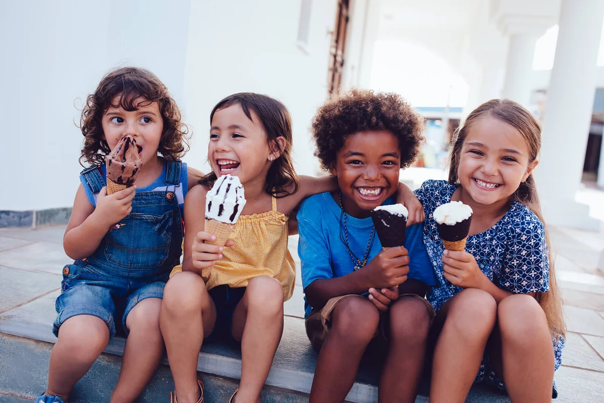 Group of cheerful children eating ice-cream in summer