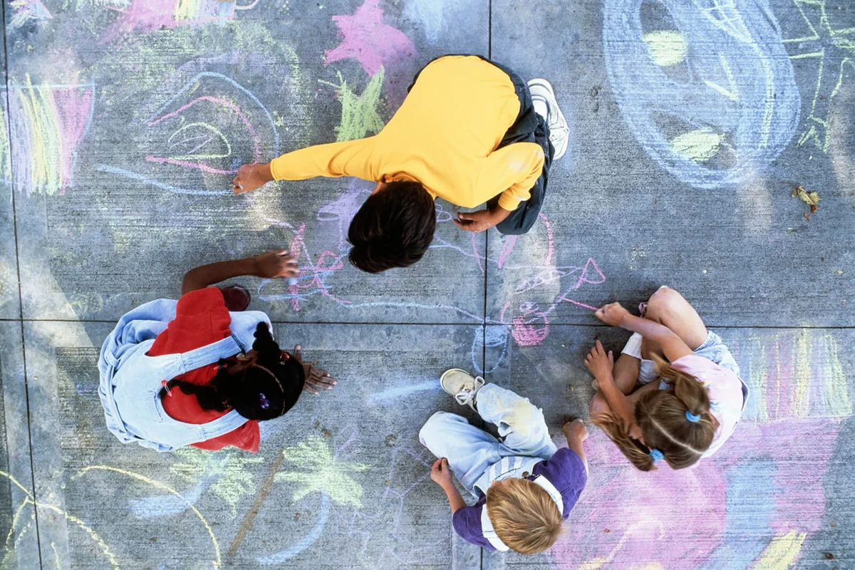 Four children drawing with chalk on pavement