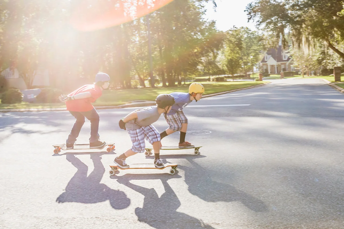 Teen friends longboarding in suburban neighborhood