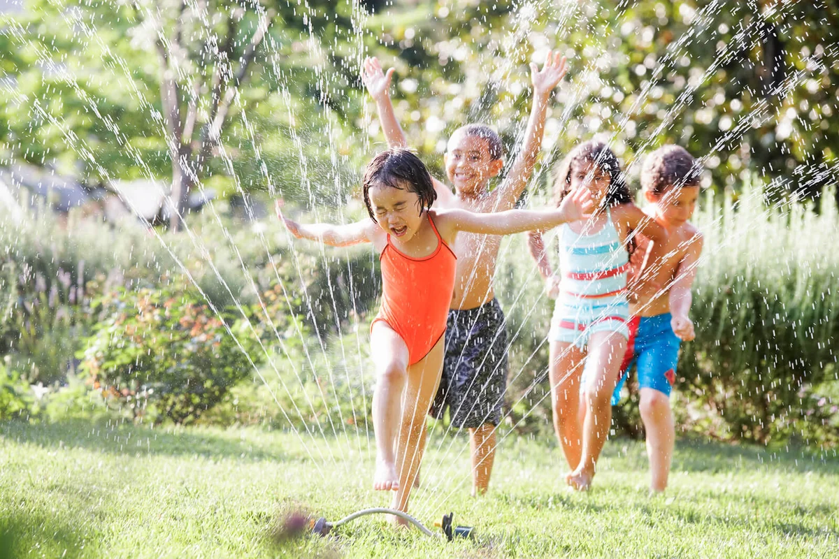 Children running through water sprinkler