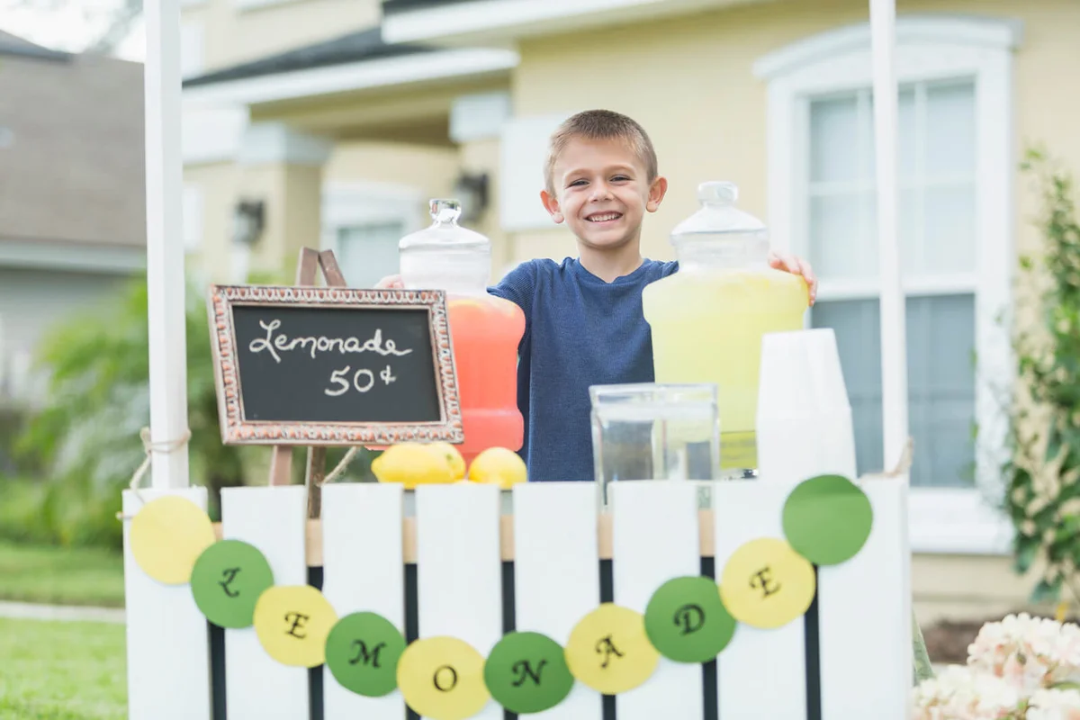 Boy selling lemonade in front yard