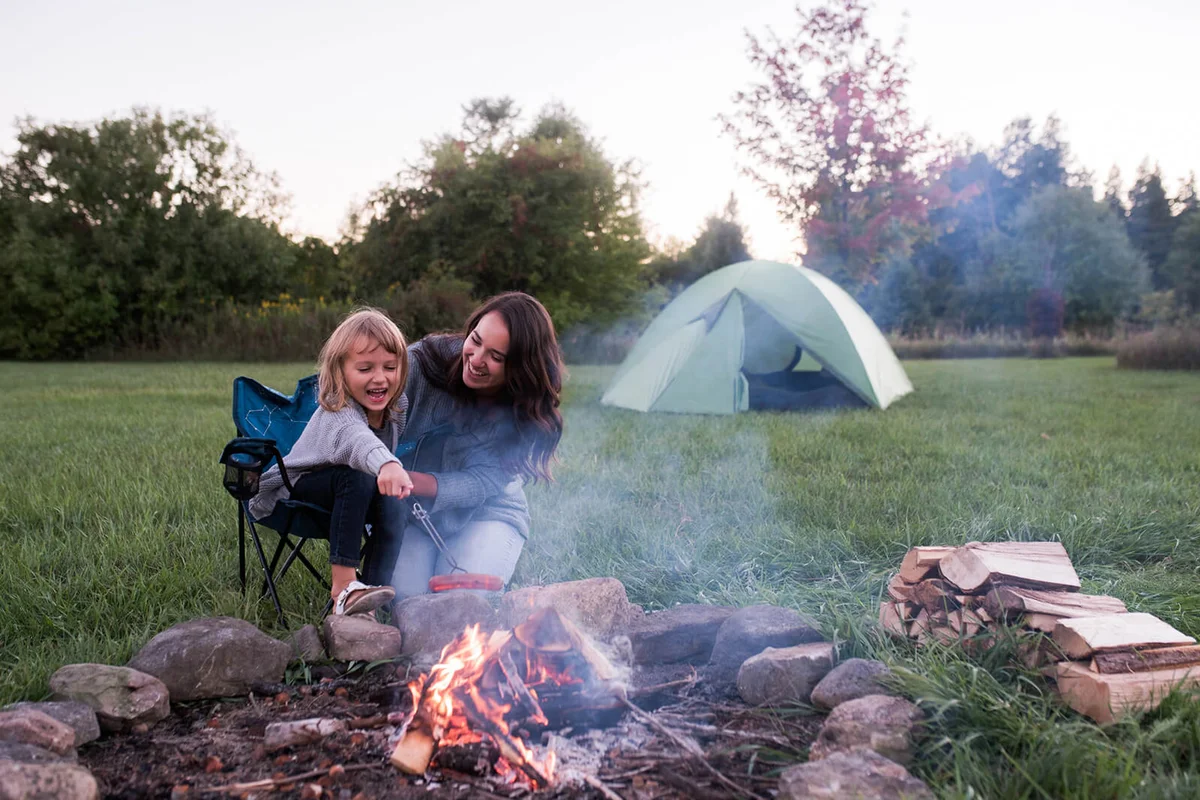 Mother and daughter sitting beside campfire