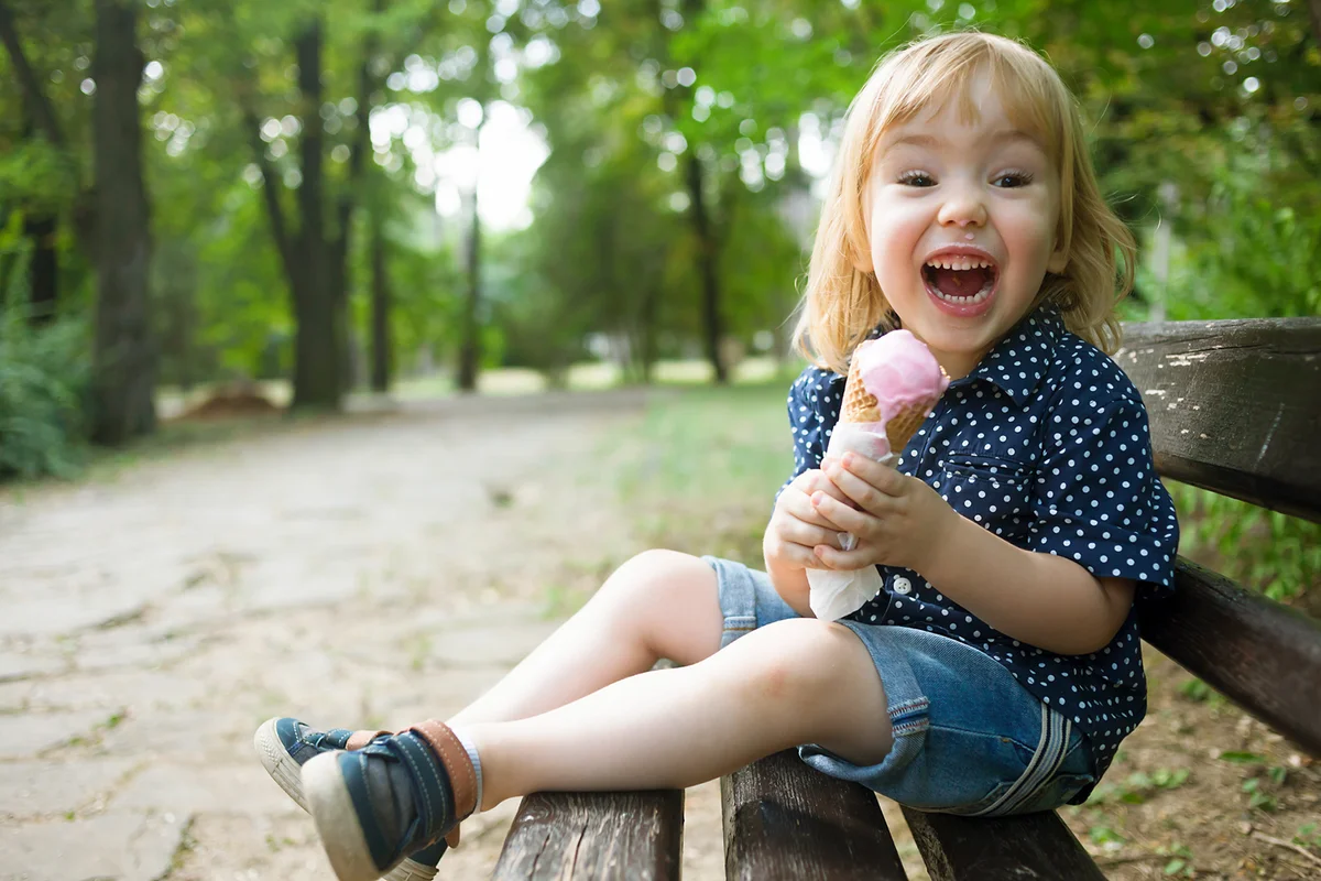 Little child eating ice cream in a park
