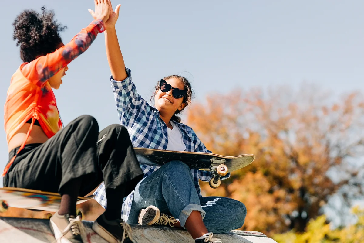 Girl skateboarders giving each other high five at skate park