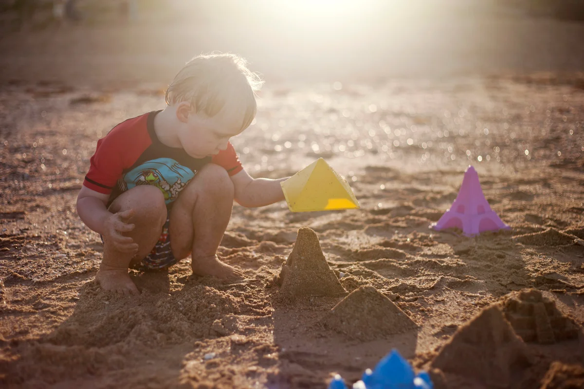 Toddler boy concentrates on building sandcastles