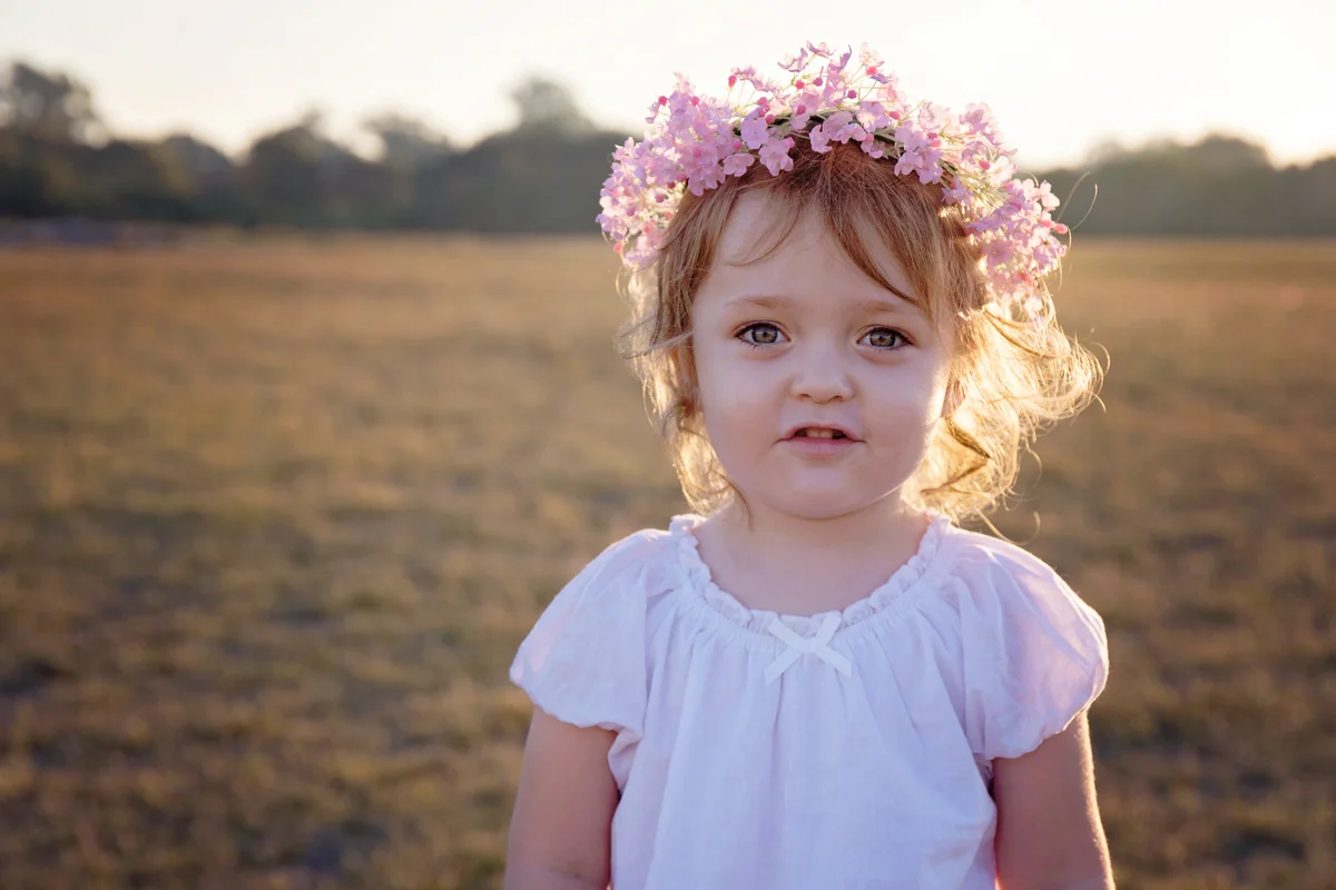 Young girl with curly hair wearing a flower crown in golden sunset light