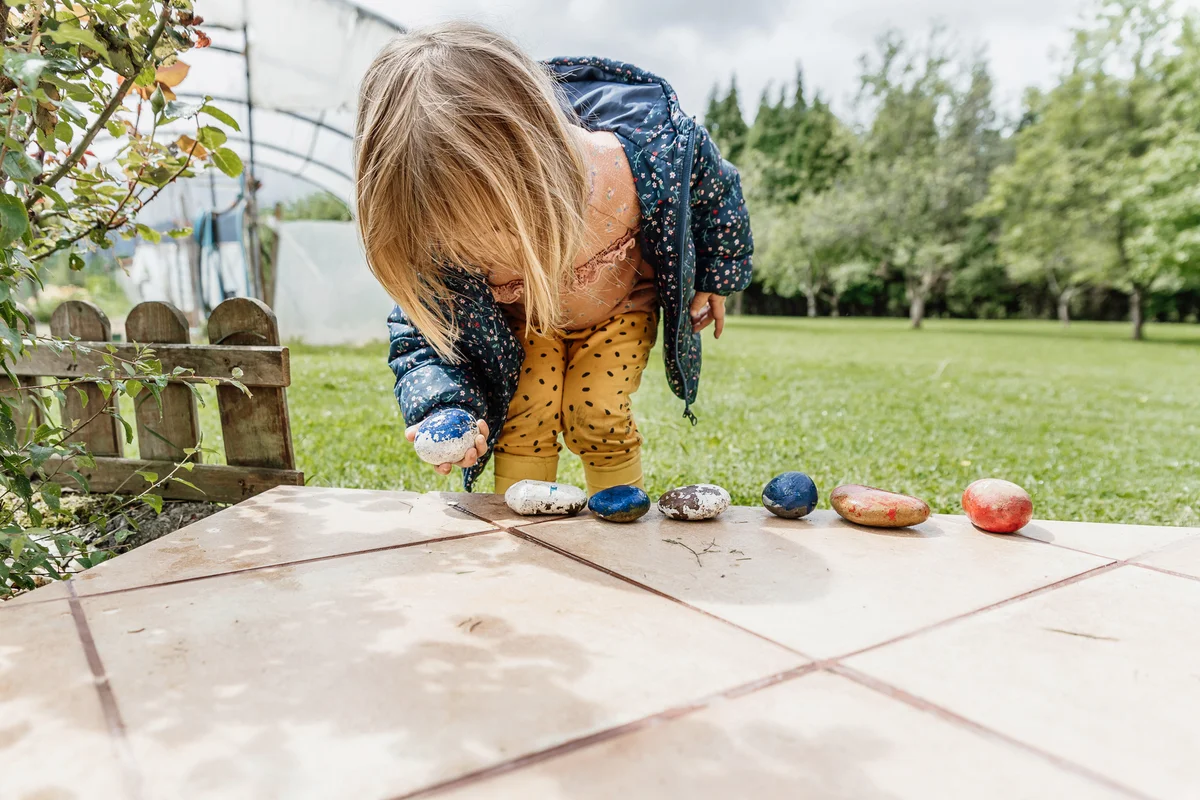 Little girl playing with stones in backyard
