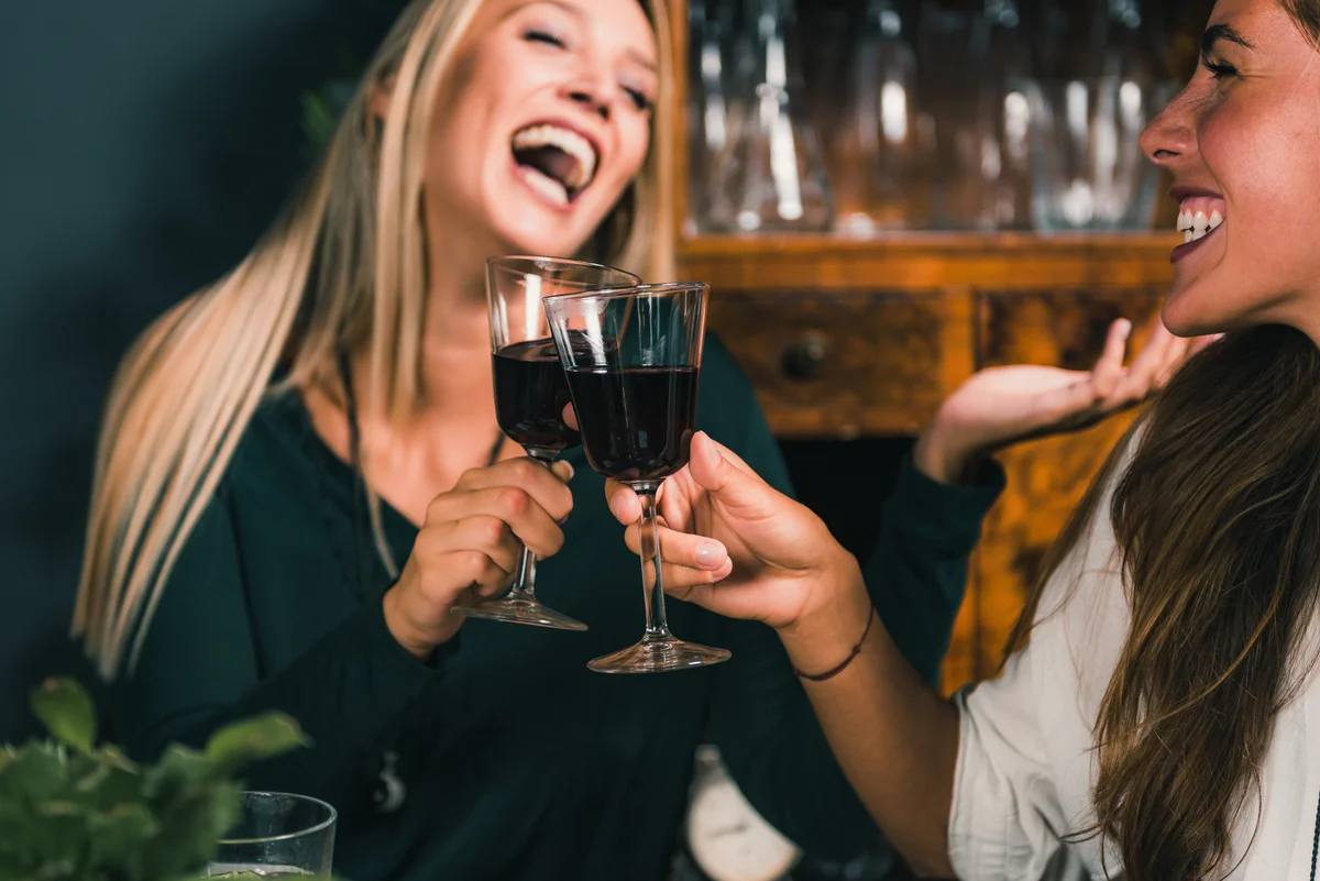 two women having fun on night out drinking wine