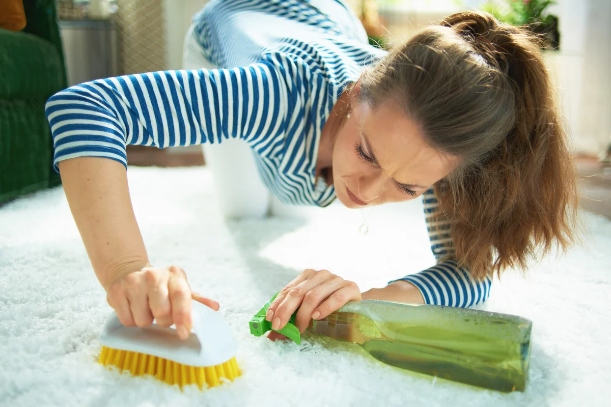 Woman with cleaning agent and brush cleaning the rug