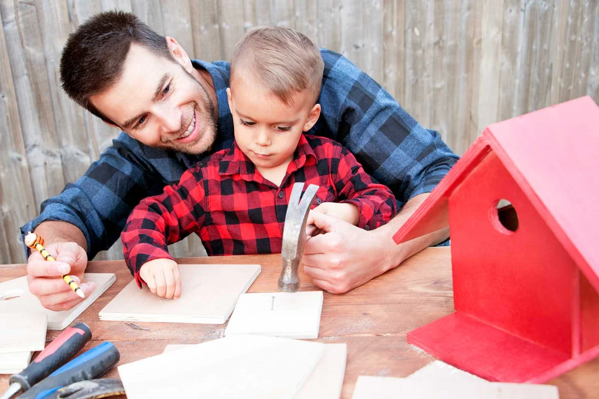father and toddler son building a birdhouse