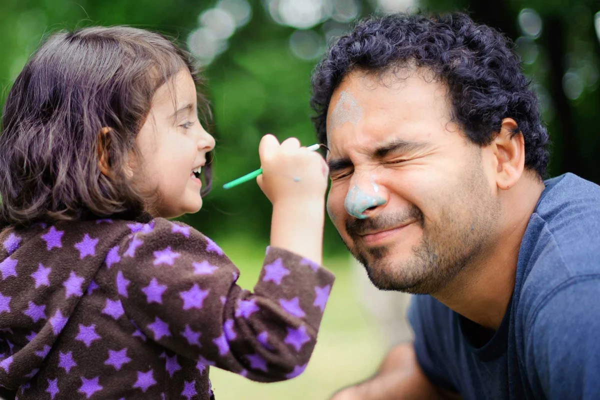 daughter putting face paint on father
