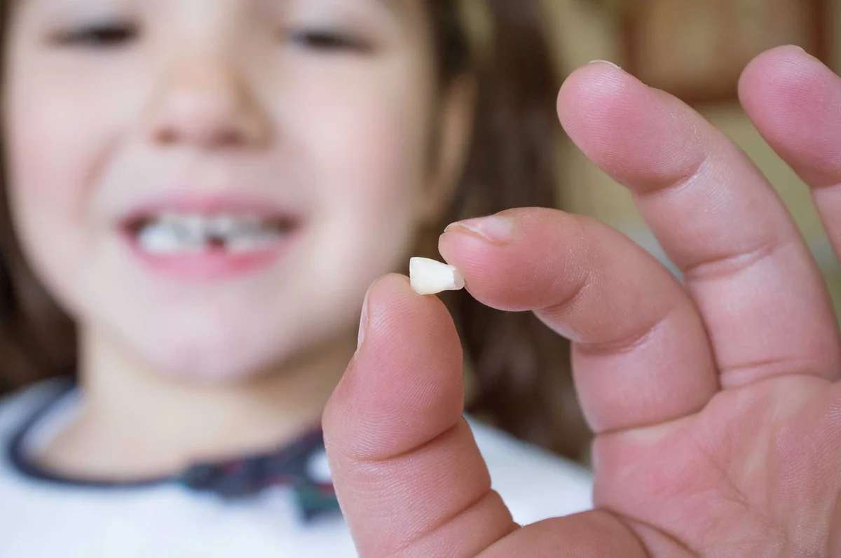 girl holding first lost tooth
