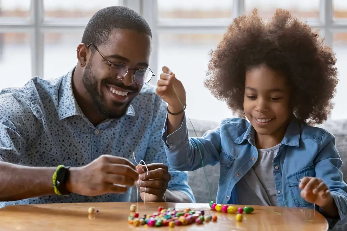 father daughter crafting string necklace with beads