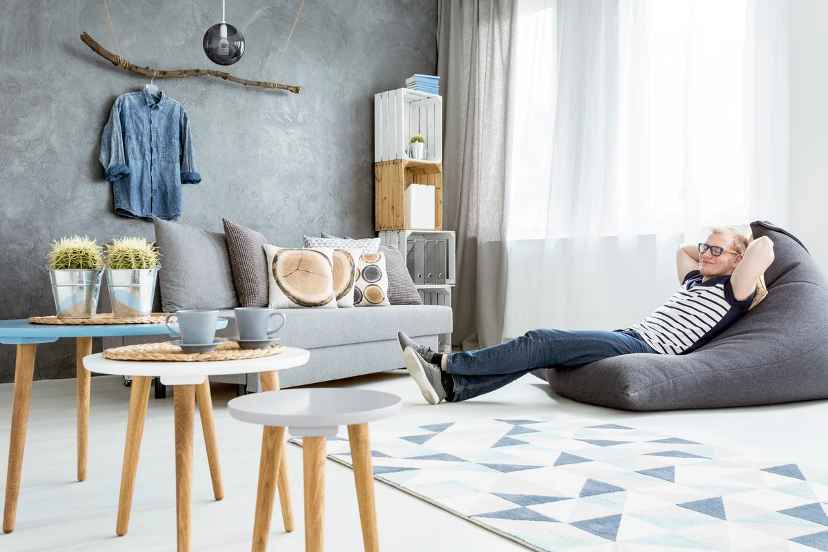Man relaxing in a modern minimalistic and bright living room in shades of cyan