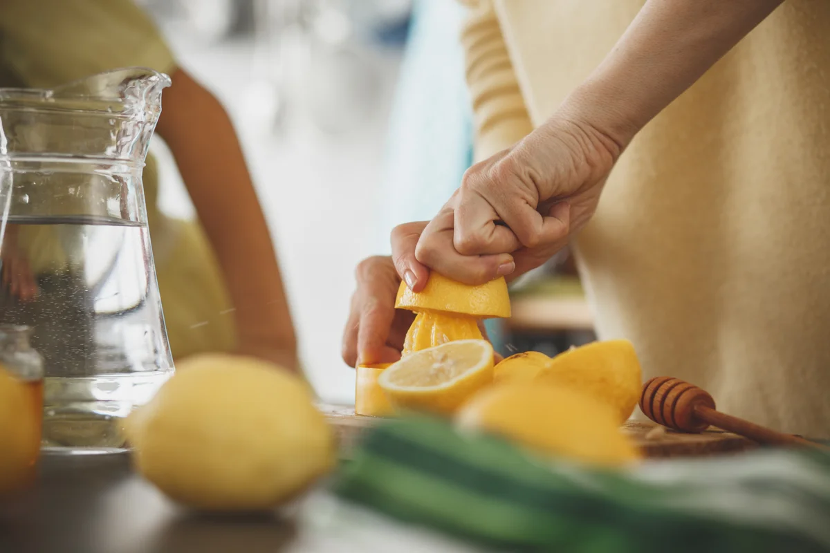 woman squeezing lemons for lemonade or lemon water