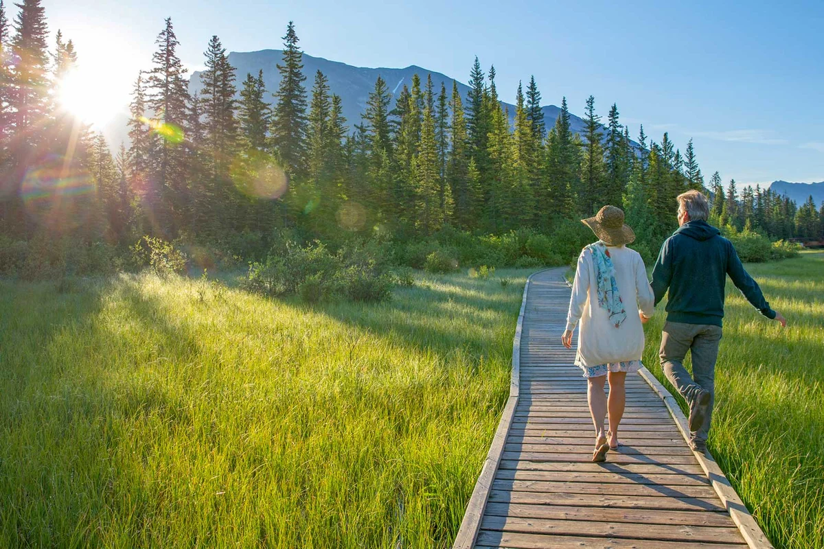 couple walking holding hands on boardwalk by mountains