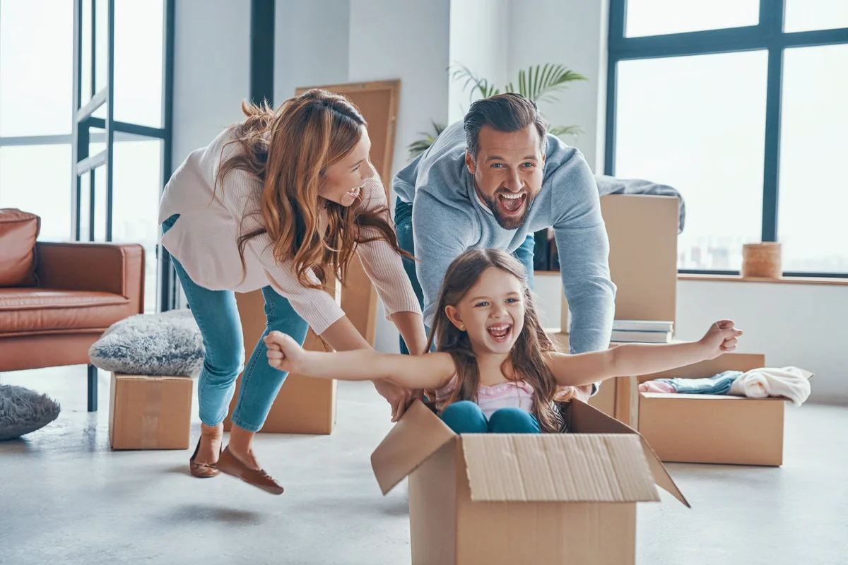 Cheerful young family smiling and unboxing their stuff while moving into a new home