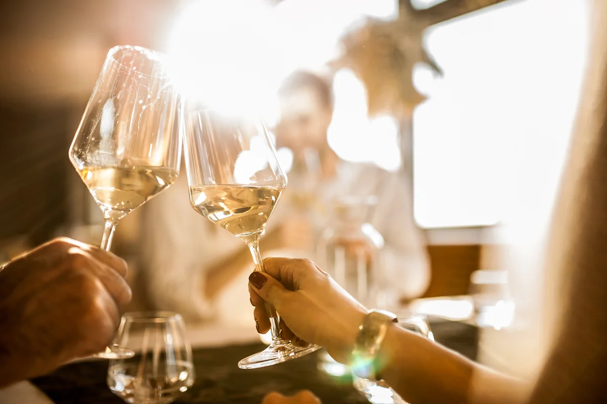 People drinking white wine at a bar