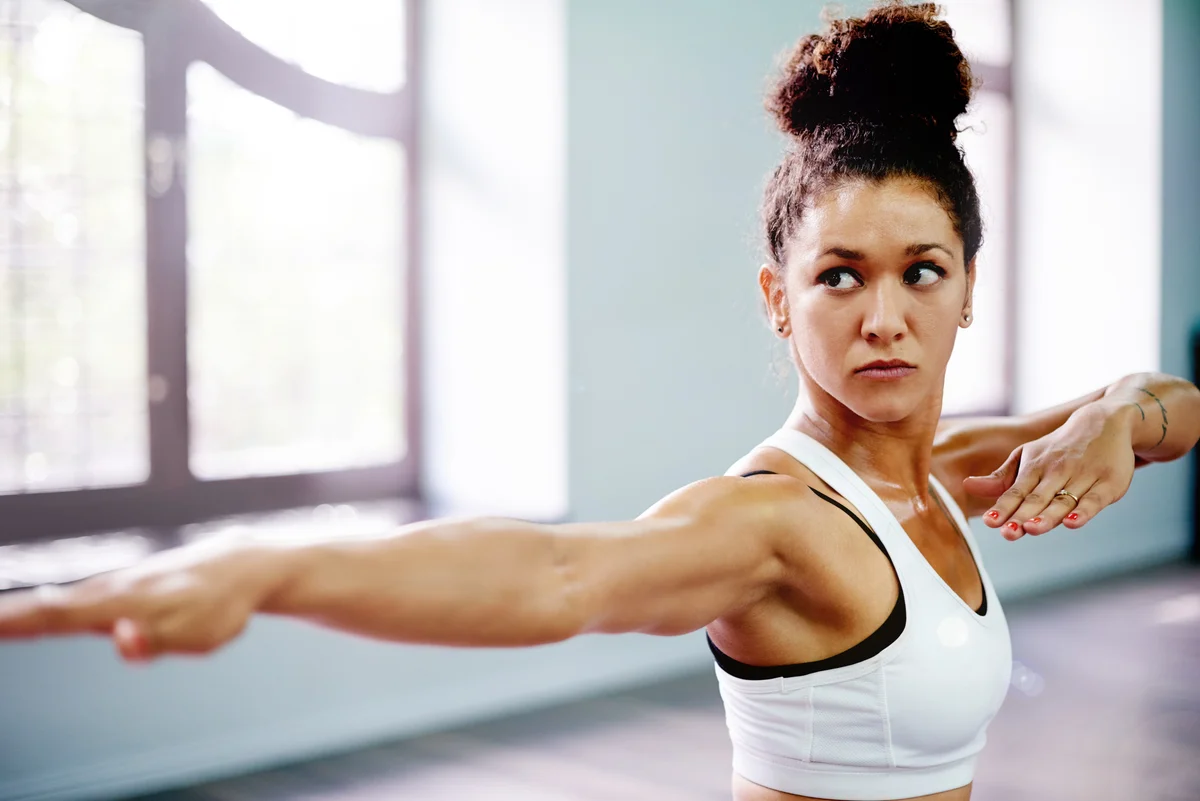 Young woman practicing a warrior pose during her yoga routine