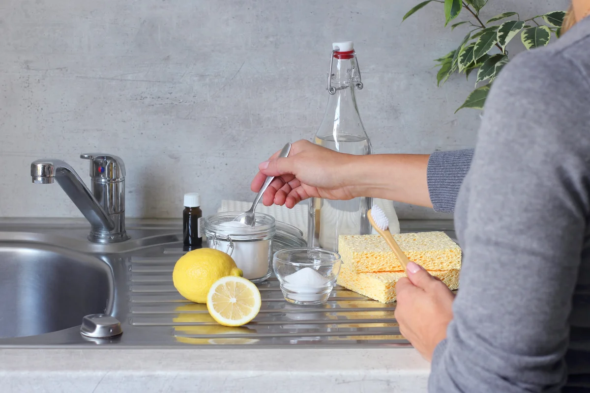 Women preparing a natural non-chemical cleaner at home with baking soda and vinegar and lemon