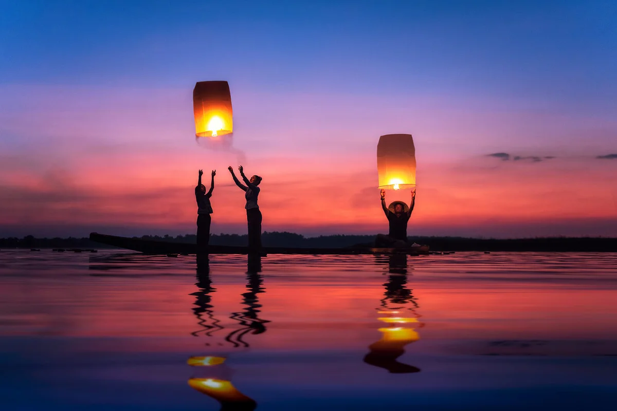 Multi-generation family flying sky lanterns on Mekong river at sunset