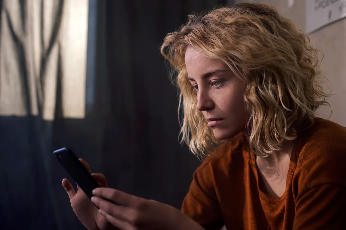 Sad woman looking at her cell phone