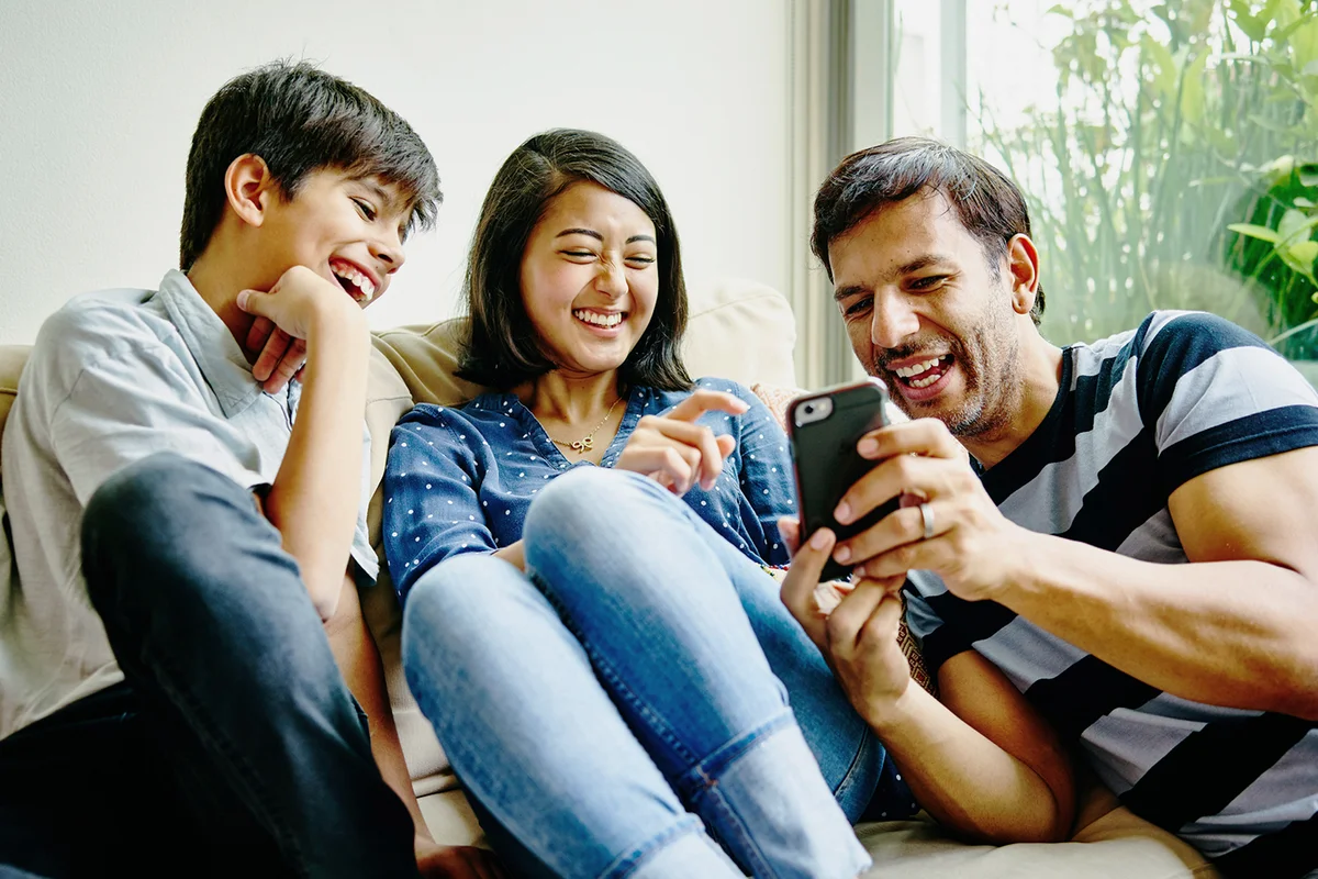 Laughing family looking at pictures on smartphone