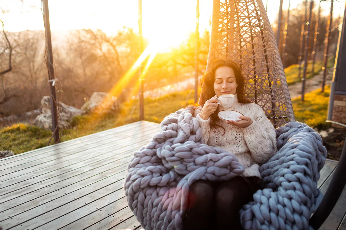 Woman drinking coffee at the beautiful terrace in the swing chair
