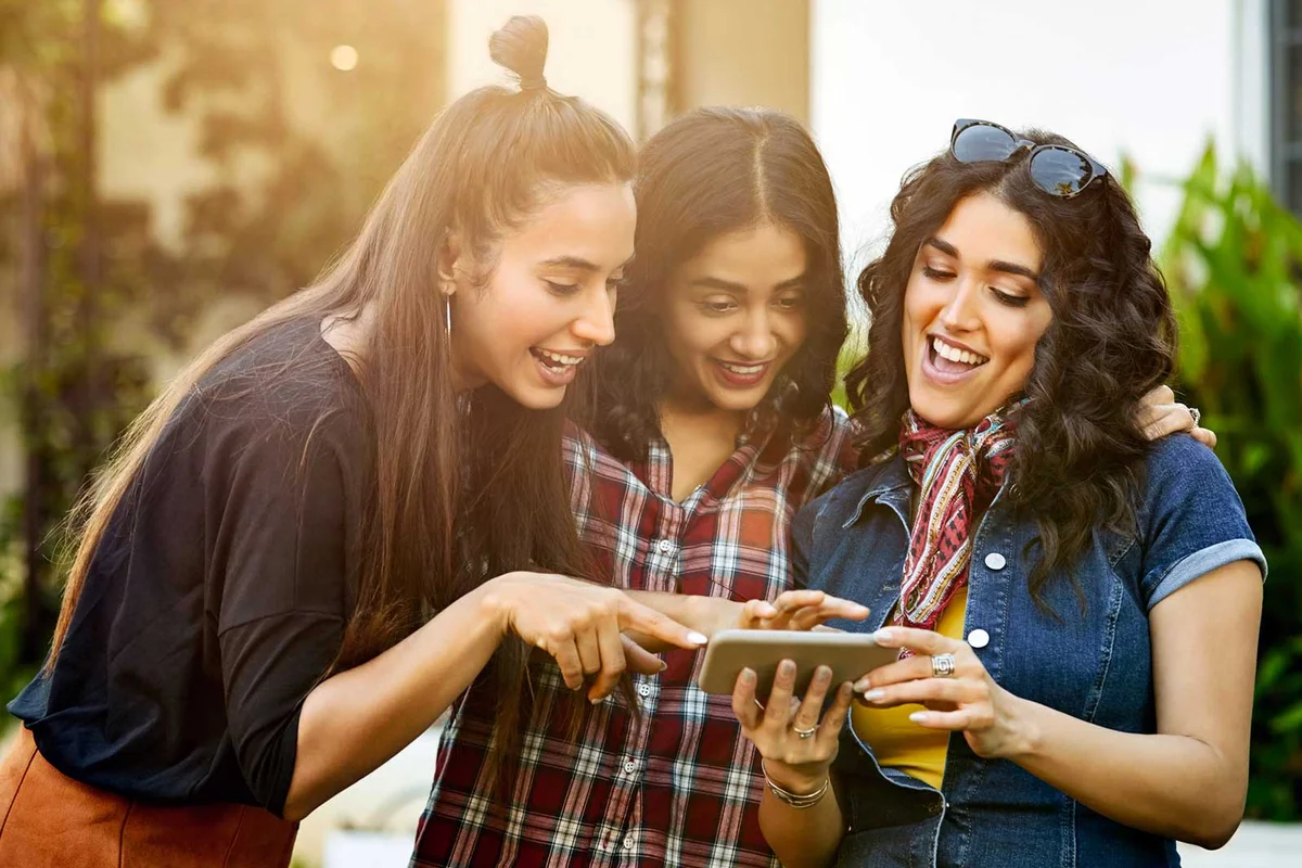 friends reading birthday social media comments on phone