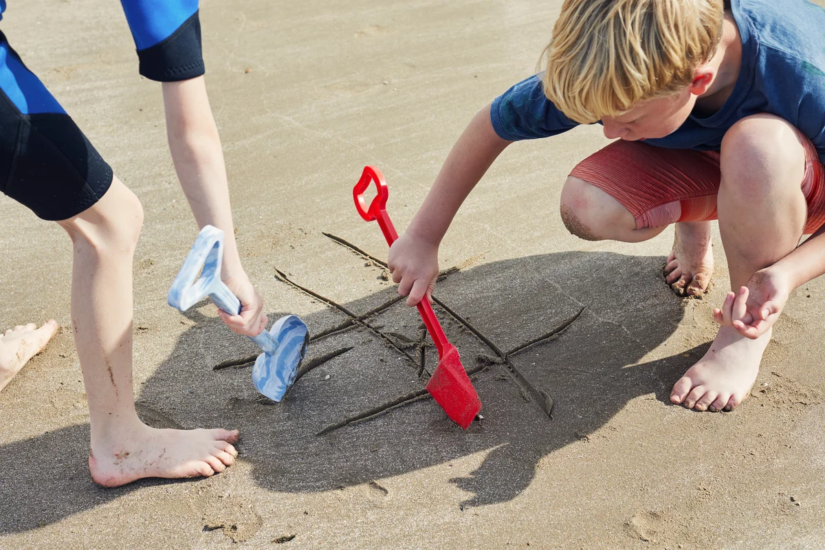boys playing tic tac toe on beach