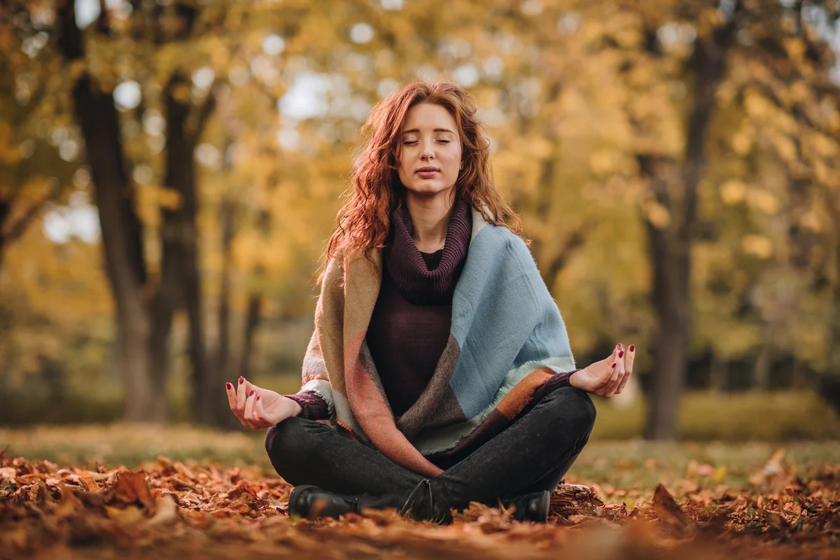 Young woman meditating in Lotus position at the park