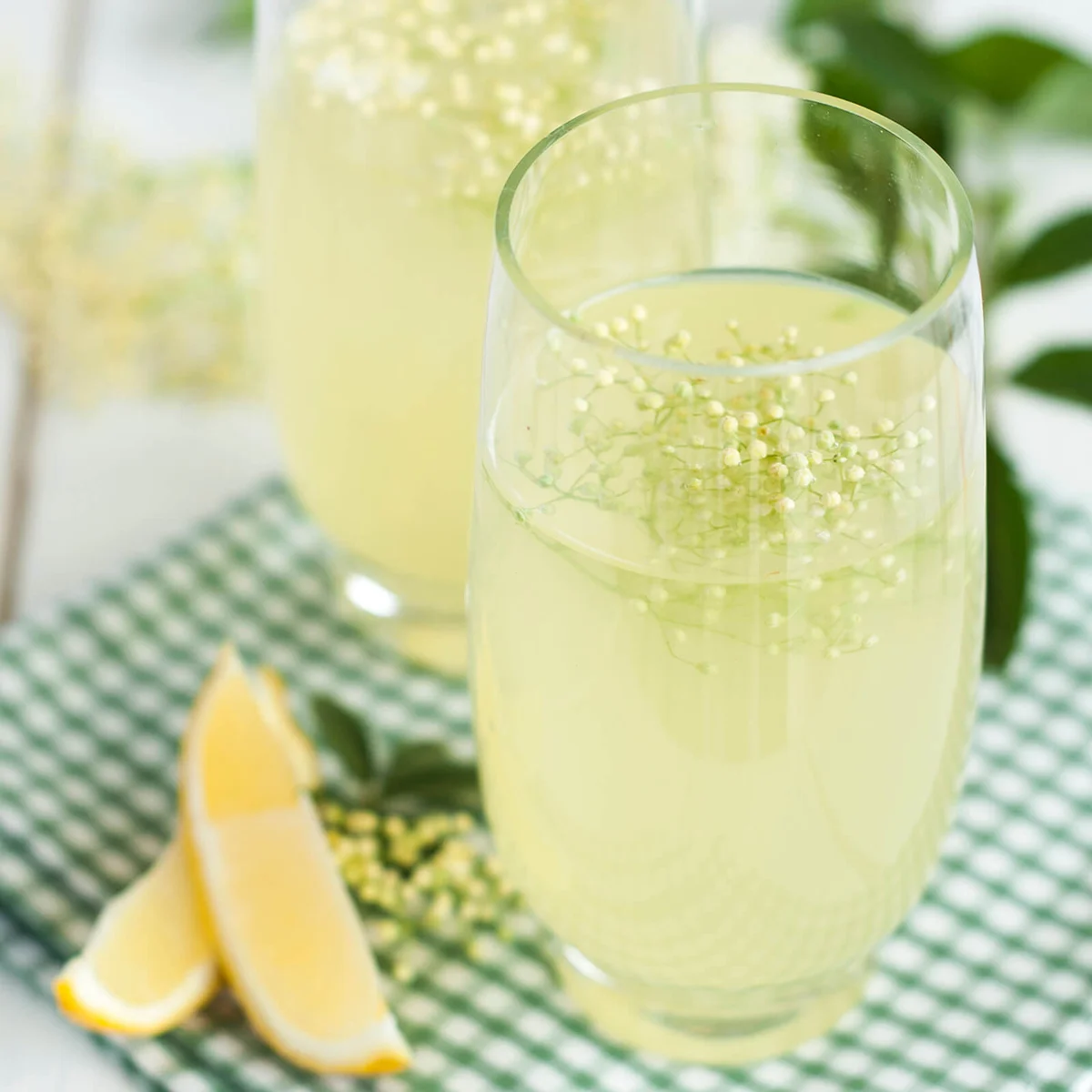 Elder flower cordial in glasses with lemon on white table