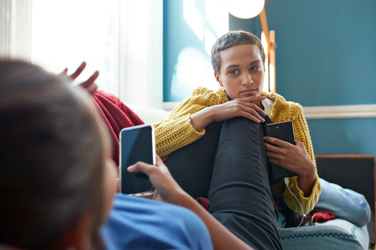 Woman listening to friend on sofa at home