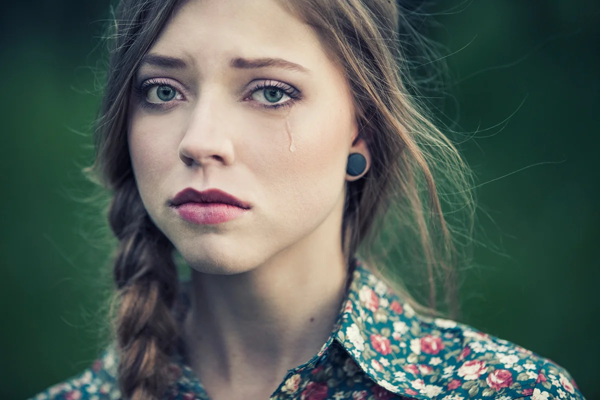 Portrait of a sad young woman with a braid, crying