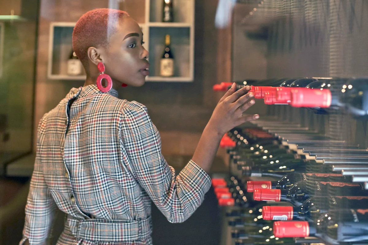 Young woman with short haircut choosing a wine in her cellar