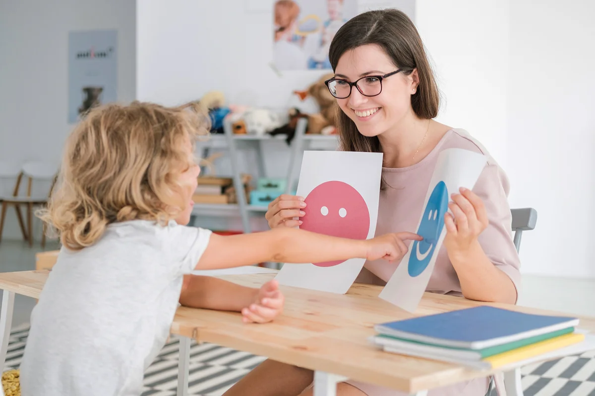 Teacher showing emotion cards to child