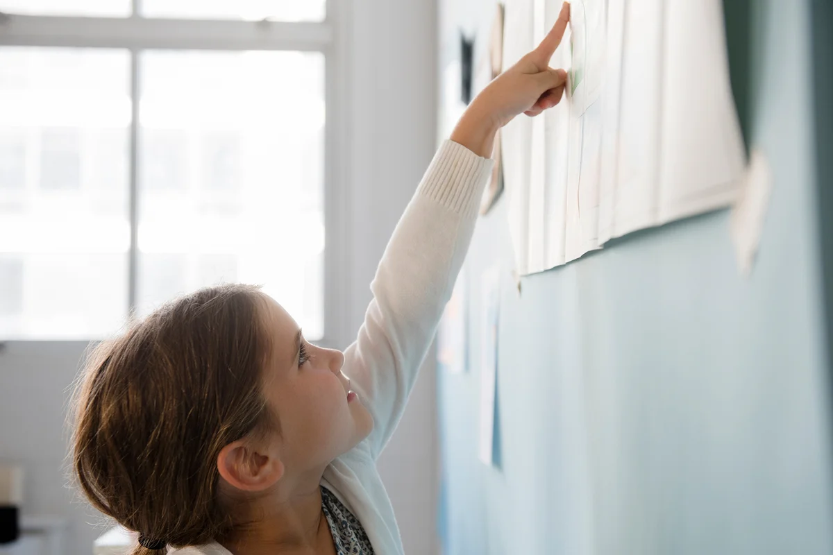 girl pointing to paper on wall