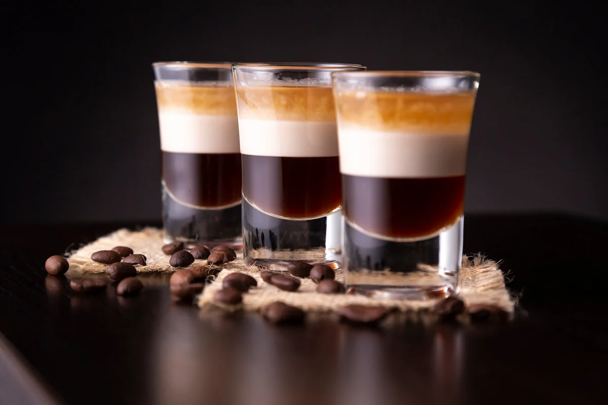 Three shots of B-52 cocktail placed on a bar counter