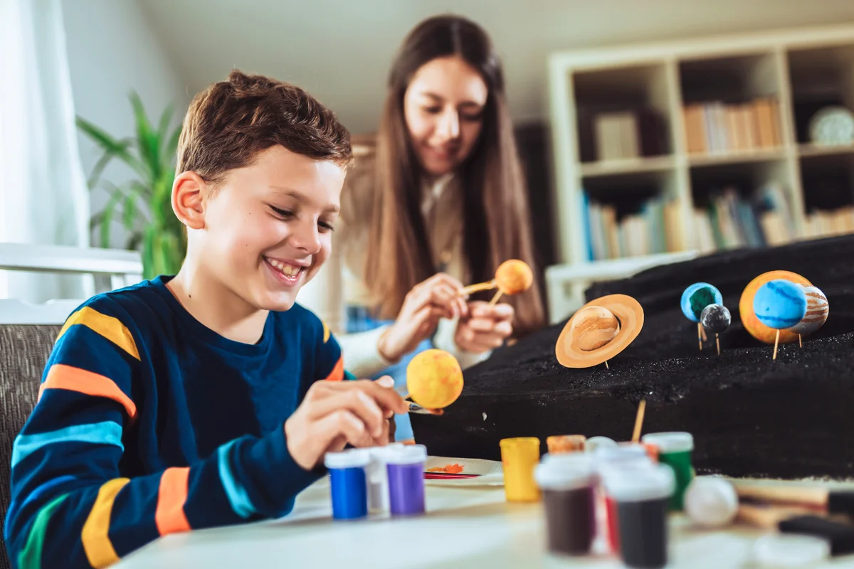 Happy school boy and girl making a solar system