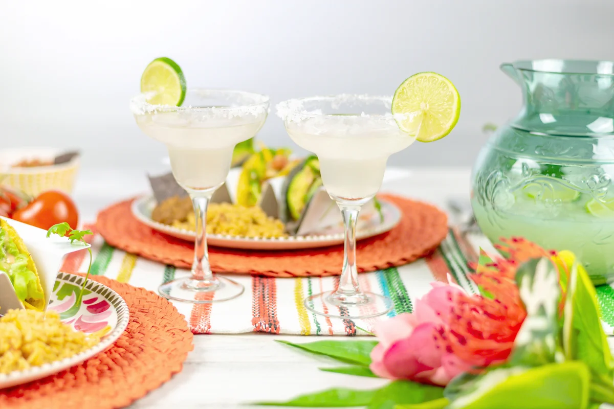 Margarita glasses with salted rim and lime and plates of tacos
