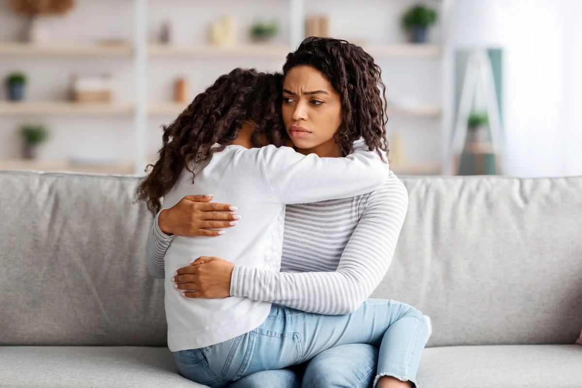 Mother hugging her daughter on the couch