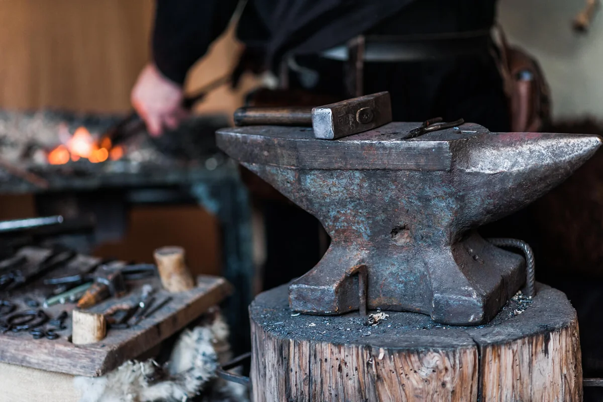 Working metal with hammer and tools on the anvil in the forg