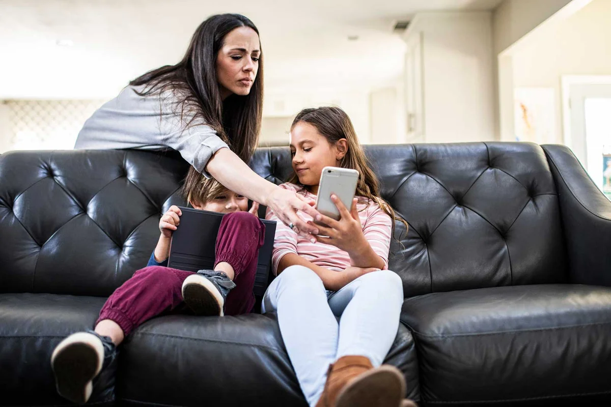 mother putting parental controls on children's phone and tablet