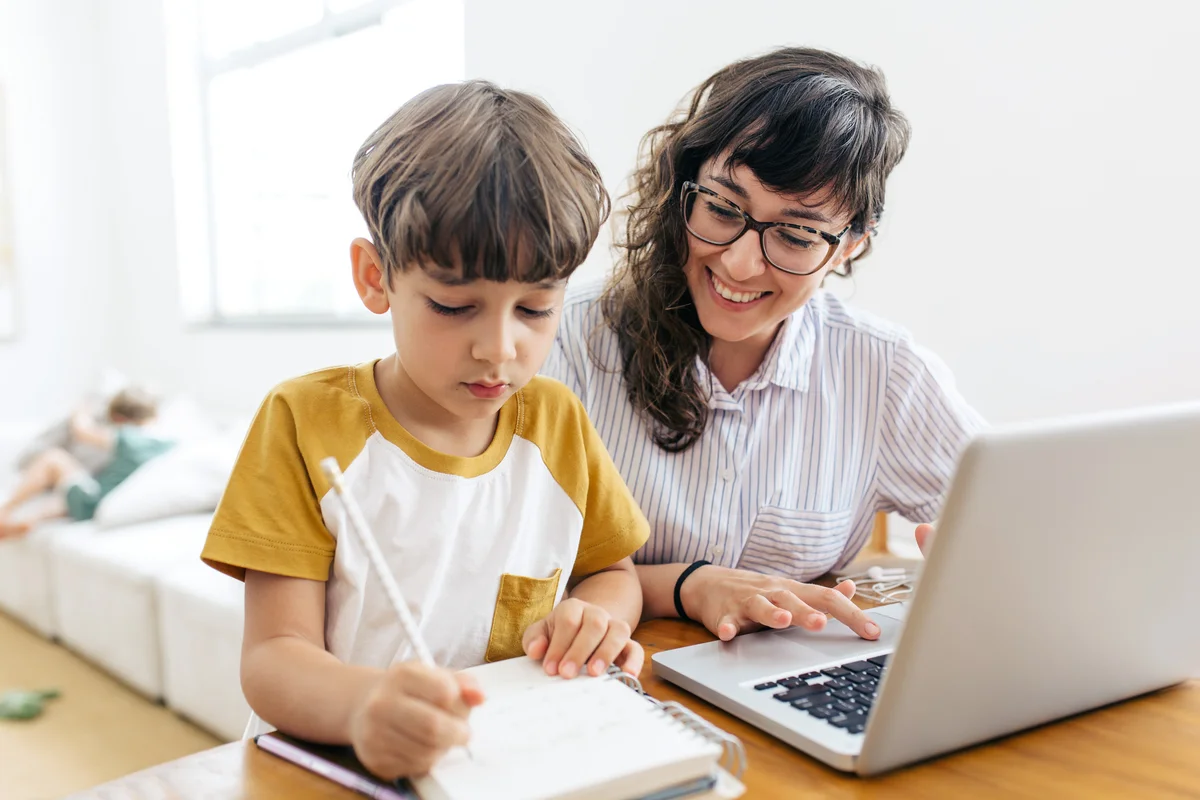 Boy doing homework while mother is working